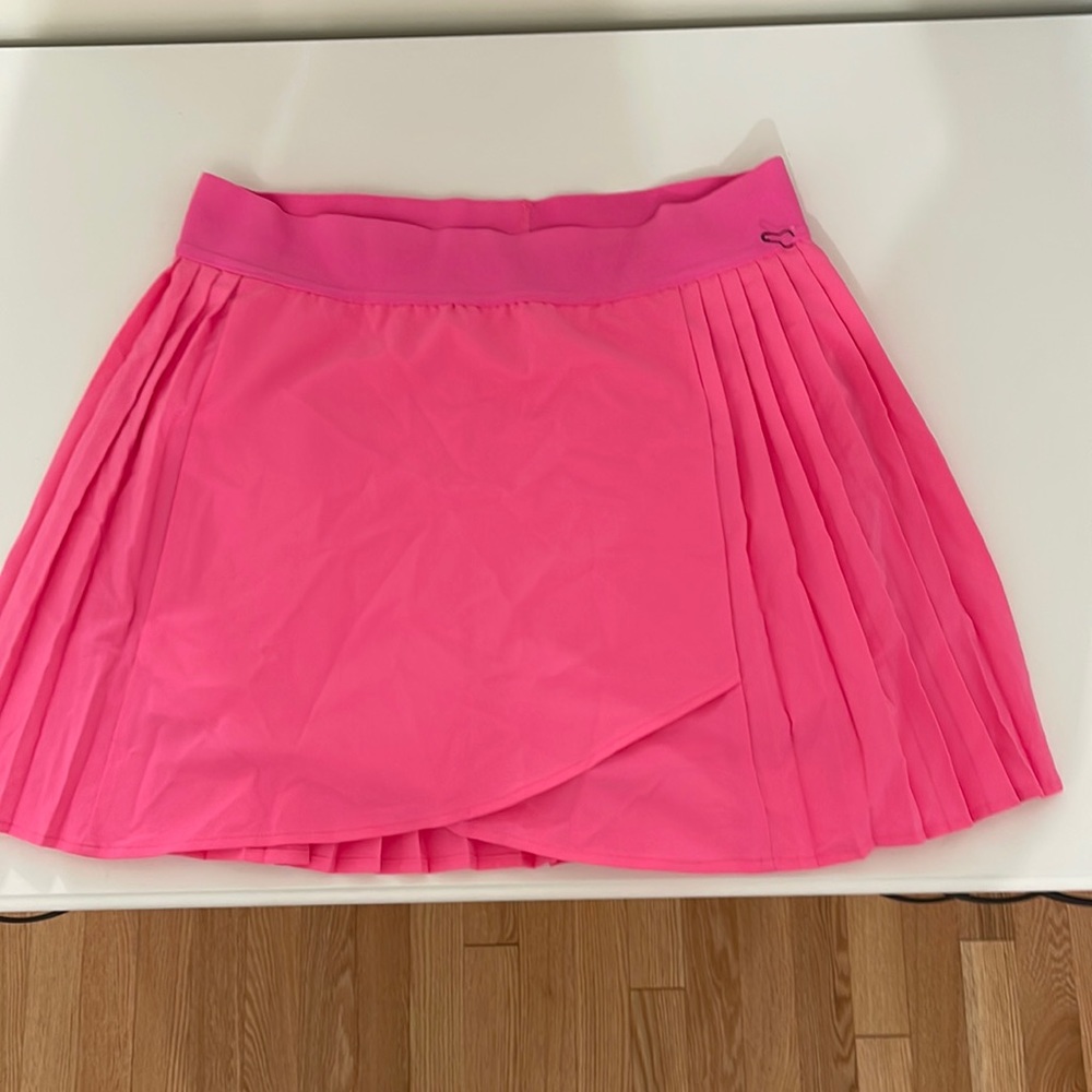 This hot pink tennis skirt is a small and the brand is KYODAN.